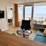Living room with sofa, armchair, and sea view.