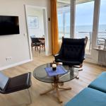 Living room with sofa, chairs, and TV. Sea view from balcony.