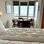 A bedroom with sea view and dining area with table and chairs.
