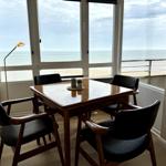 Dining table with four chairs in front of large window with sea view.