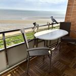 Terrace with table and chairs, view of beach and sea, bird on railing