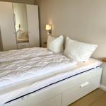 Bedroom with white bed, nightstand, and mirrored wardrobe