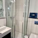 Bathroom with shower, sink, and toilet. Wall art with fish motif.