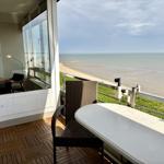 Terrace with table and chairs offers sea view. Wooden floor and glass wall visible.