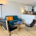 A living area with a blue sofa, two black chairs, and a round table.