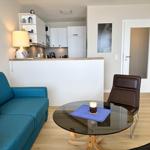 Blue sofa with orange cushions, round glass table, and brown chair in the living area.