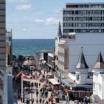 Blick auf belebte Straße mit Meer im Hintergrund und markanten Gebäuden.