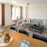 Wohn- und Essbereich mit Sofa, Esstisch und Fenstern.