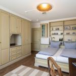 Schlafzimmer mit Kleiderschrank, Bett und Bücherregal an der Wand.