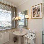 Badezimmer mit Waschbecken, Spiegel, Dusche und Fenster mit Blick.