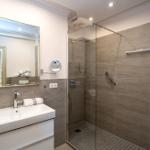 Badezimmer mit Dusche, Waschbecken und Spiegel