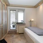 Schlafzimmer mit Bett, Kleiderschrank und Fenster mit Blick auf Balkon.