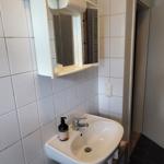 Badezimmer mit Waschbecken, Spiegelschrank und Holzunterschrank.