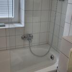 Bad mit Badewanne, Duschbrause und Fenster mit Jalousie