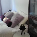 Schlafzimmer mit Bett, Kissen, Nachttisch und Schrank.