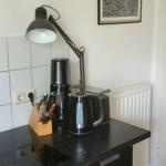 Küchenzeile mit Kochfeld, Kaffeemaschine, Wasserkocher und Stehlampe.
