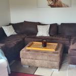 Ein Wohnzimmer mit braunem Sofa, einem Kissen und einem Bild an der Wand.