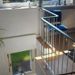 Treppe mit Geländer führt zu einem Raum mit großem Fenster und Blick auf Grün.