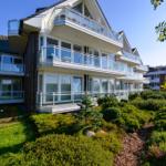 Moderne Ferienwohnung mit Balkonen und Garten. Sicht auf mehrere Etagen mit Glasgeländern.
