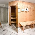 Sauna mit Holzbank und Duschbereich mit Glaswand.
