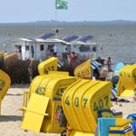 Strand mit gelben Liegestühlen und einem Strandhaus im Hintergrund.