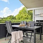 Deck with table, chairs, grill, and view of green areas.