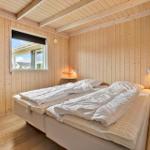 Bedroom with wooden walls, double bed, and window with view.