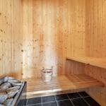 Sauna with wooden walls, bench, and stone tray with bucket.