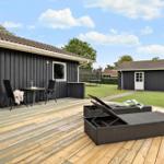 Deck with loungers and table in front of a house with dark cladding.
