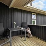 Deck with table, two chairs, flowers, and view of green areas.