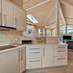 Modern kitchen with wooden elements and view into living area.