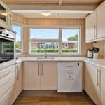 Kitchen with wooden walls, window, sink, dishwasher, and kitchen appliances.