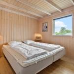 Bedroom with wooden walls, bed, window, and mirror.