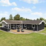 Black house with wooden terrace and garden. Outdoor area with seating.