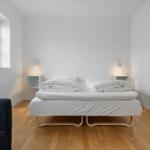 Schlafzimmer mit Bett, Fenster und Holzboden.
