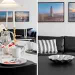 Essbereich mit Tisch, Stühlen und Wandbildern. Wohnbereich mit Sofa, Kissen und Tisch.