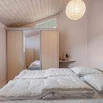 Schlafzimmer mit Bett, Schrank und Fenster. Decke aus Holz, Lampe und Nachttisch.