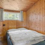 Schlafzimmer mit Holzwand, Bett, Fenster und blauem Schrank.