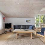 Wohnzimmer mit Sofa, Tisch und Stühlen. Holzdecke und große Fenster.