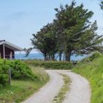 Gehweg führt zu einem roten Haus mit Blick aufs Meer.