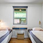 Two single beds in a room with wooden floor and white wall paneling. A window and a desk are visible.