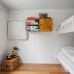 Childrens room with bunk bed, wooden shelf, and toys.