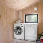 Washing machine and dryer in wooden room with window and refrigerator.