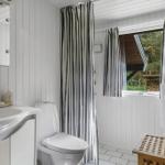Bathroom with sink, toilet, shower, and window overlooking outdoor area.