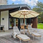 Deck with lounge chairs and umbrella in front of modern house with garden.