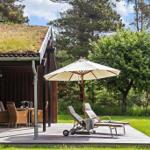 Deck with lounge chairs, umbrella, and grill. Lawn and trees in the background.