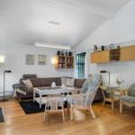 Living room with sofa, chairs, and wooden floor. Wall shelves and fireplace visible.