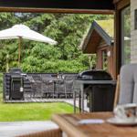 Deck with grill, table and chairs under a white umbrella.