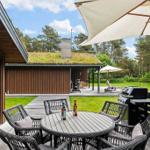 Deck with table, chairs, and grill. Lawn and forest in the background.