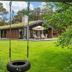 House with grass roof, terrace, and garden. A tire swing hangs in the foreground.